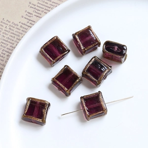 Macro view of purple square glass beads with gold edges for DIY jewelry making