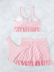 Gedetailleerde weergave van roze driedelige bikini met opengewerkte bloemen en ruches