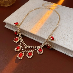 Macro detail of luxury golden necklace with red teardrop crystal pendants and shiny rhinestones