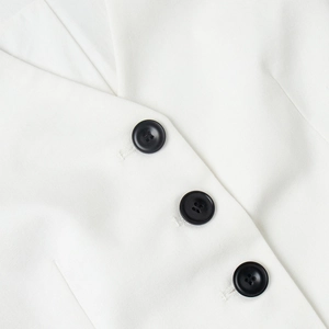 Detailed view of white V-neck vest showing black contrast buttons and twill fabric texture