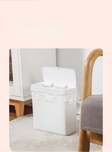 Detail showing white slim trash can with lid in living room setup between furniture
