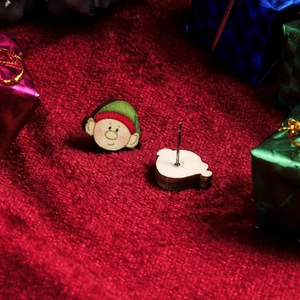 Close-up of wooden Christmas elf earrings with hand-painted details on red velvet background