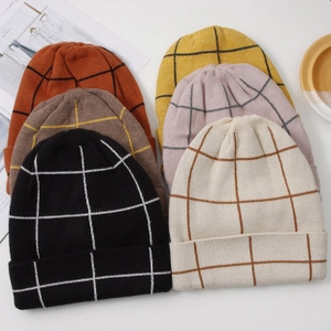 Flat lay of colorful grid pattern knitted beanies in black, cream, orange, and brown