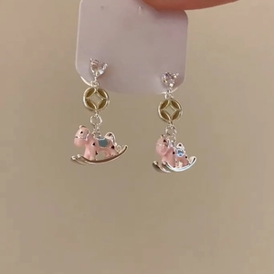 Detail of pink enamel rocking horse earrings with heart-shaped zircon studs and gold coin links