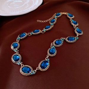 Détail d'un collier vintage avec gemmes ovales bleu foncé et métal bronze sur tissu