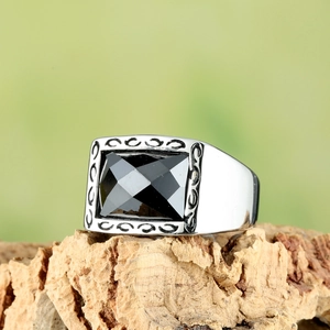 Bague pour homme en acier titane avec pierre noire sur socle en bois rustique
