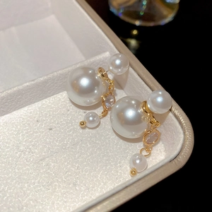 Detail of elegant double-sided pearl earrings with gold chain and zircons in jewelry box