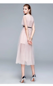 Détails d'une robe en maille rose avec col en dentelle et fine ceinture noire