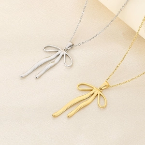 Detailed view of gold and silver bow-shaped pendant necklaces on a textured fabric base