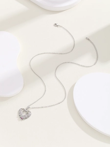 Detail of silver heart necklace with angel wings and a pink gemstone center