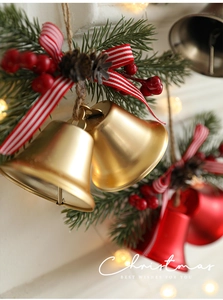 Detail von goldenen Weihnachtsglocken mit Tannennadeln, Beeren und gestreiftem Band