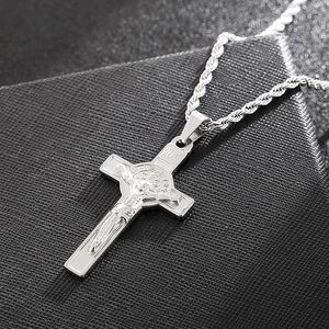 Macro detail of silver cross pendant with St. Benedict medal and twist chain design