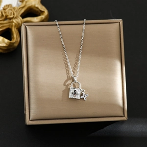 Dettaglio del ciondolo a lucchetto d'argento e fiore su una collana elegante