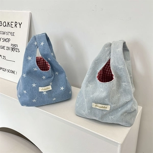 Detail of denim wrist bags with star and bow patterns featuring red checkered lining