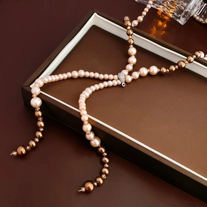Detailed view of layered champagne and brown pearls with a diamond pendant in a gift box