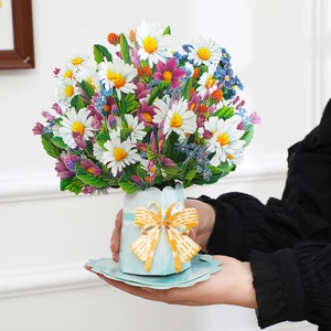 3D pop-up flower bouquet card with blue vase and yellow bow detail held in hand