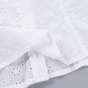 Détail de tissu en dentelle jacquard blanche avec broderies délicates et texture ajourée