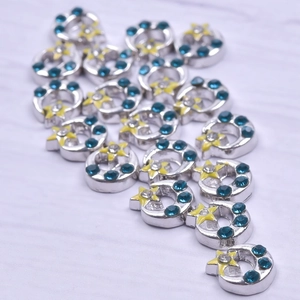Macro view of silver crescent moon and star charms with blue and yellow crystals