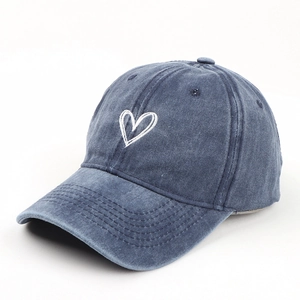 Detail of washed blue cotton baseball cap with white heart embroidery and vintage texture