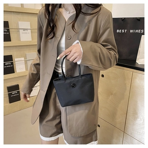 Détail du sac à bandoulière en nylon noir avec boucle ronde et poignée supérieure