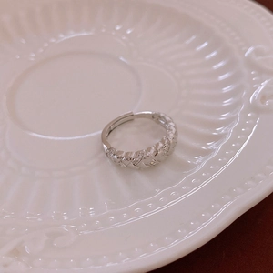 Detailed view of silver twist ring with inlaid zircons in a vintage ceramic dish