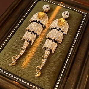 Detail view of vintage pearl drop earrings with yellow gemstones on velvet display