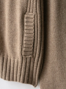 Detailed macro view of the cable-knit texture and side pocket on the brown knit cardigan