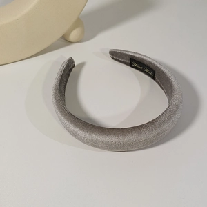 Detail showing hand made label on silver velvet padded headband with soft shadows