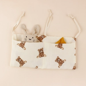 Detail of cotton muslin baby bedside organizer with dual pockets and brown bear print