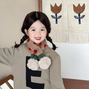 Close-up of beige knitted kids scarf with red floral patterns and white pom-poms