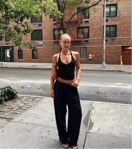 Street style shot of a woman in a black deep V-neck halter vest and wide-leg trousers