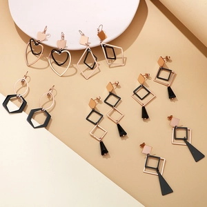 Gros plan de boucles d'oreilles géométriques en or rose et noir mat, formes variées