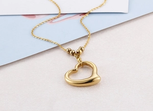 Close-up of golden heart pendant necklace with bead details on polished gold chain