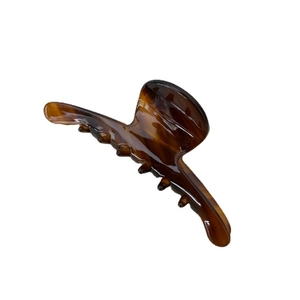 Minimalist tortoiseshell acetate hair claw clip with elegant amber pattern on white background