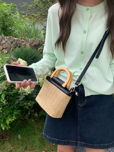 Straw bucket bag with wooden handle and black leather trim for beach crossbody style