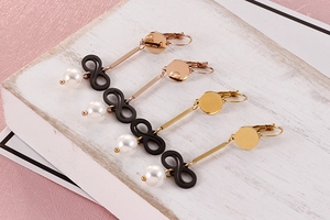 Macro view of long pearl drop earrings with black infinity symbol and gold finish