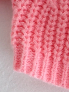 Vista macro dettagliata del polsino di un maglione rosa a maglia grossa a coste