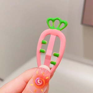 Macro view of pink carrot-shaped hair clip with candy color drip oil finish and green leaves