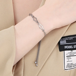 Adjustable silver stainless steel hollow cross bracelet worn on model with chic fabric background