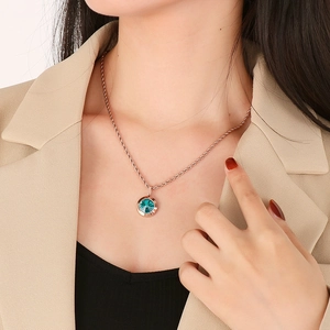 Close-up of a gold twist chain necklace with a round turquoise stone pendant on model
