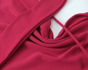 Dettaglio del tessuto dell'abito lungo fucsia con spalline sottili e pieghe morbide