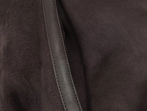 Detail of dark brown suede fabric with premium faux leather trim on a reversible jacket