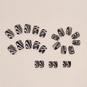 Black and white wavy press-on nails with silver glitter details on beige background