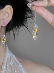Detail view of long tassel earrings with sparkling glass crystals and metallic chains