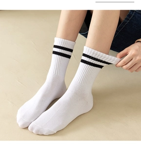 Close-up of white cotton crew socks with black stripes on model in minimalist setting