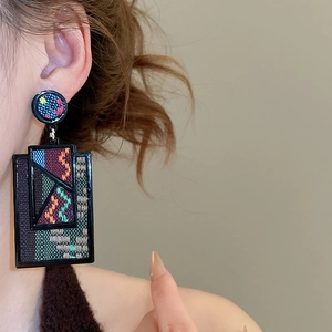 Detail of bohemian geometric rectangular earrings with colorful woven ethnic patterns