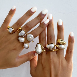 Baroque golden rings with irregular white pearls on hand in a close-up shot