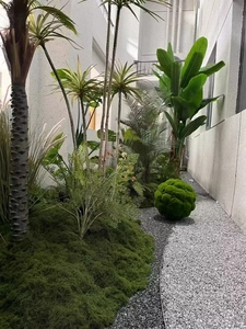 Detail of artificial green moss lawn with faux palm trees and tropical landscape decor