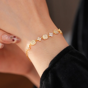 Detail of gold-plated bracelet featuring floral and square links with white zircons