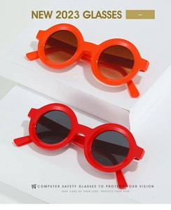Detail of round children's sunglasses in orange and red plastic frames on white blocks